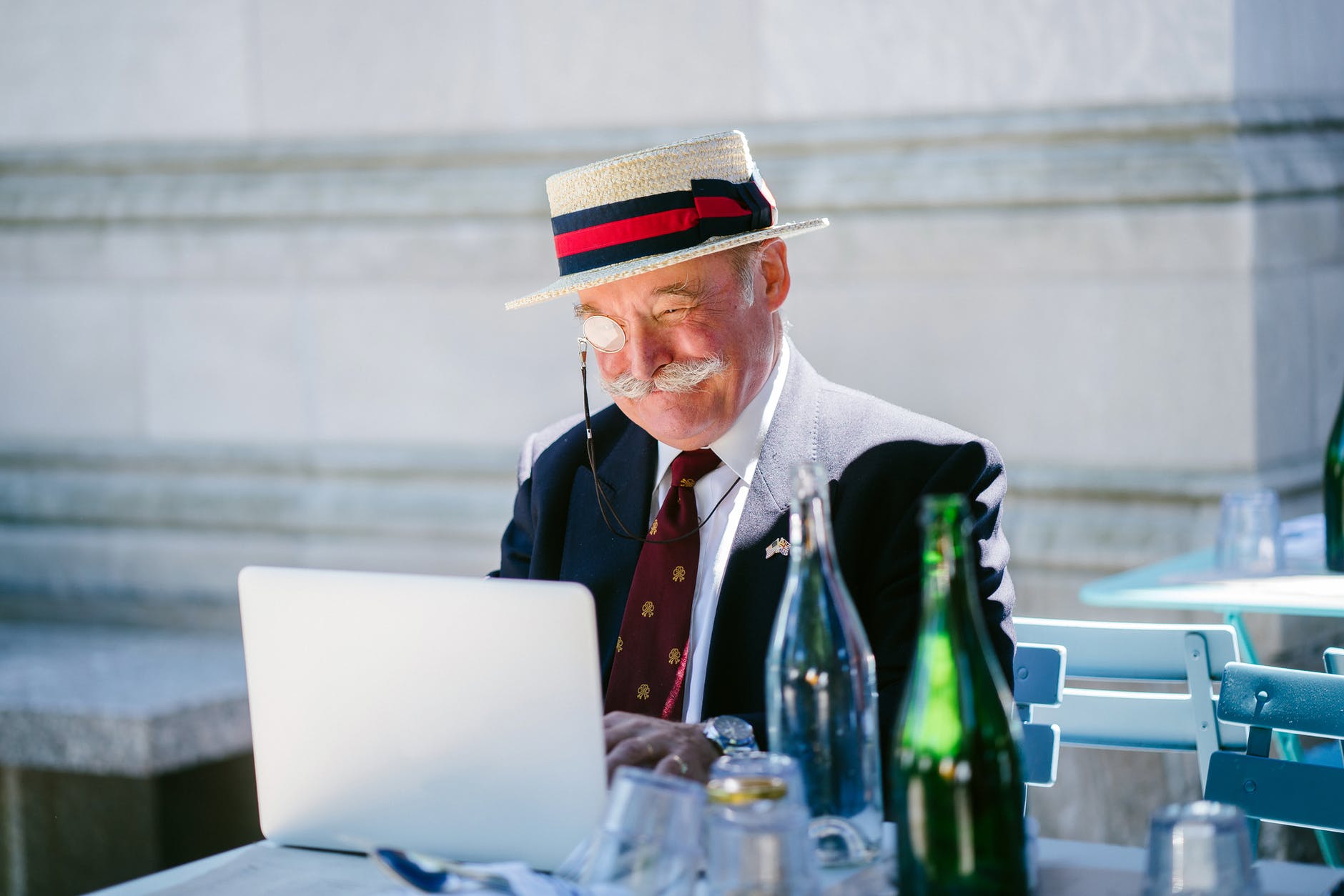 older eccentric man using laptop at a restaurant outdoors
